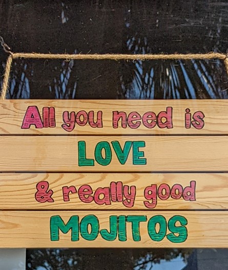 A sign with “All you need is love and really good mojitos”